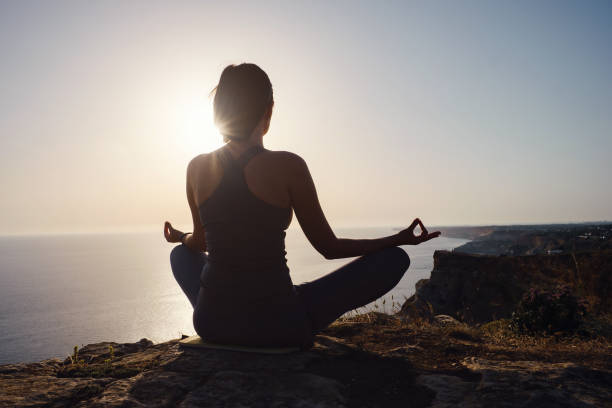 istock Young woman practicing yoga over sunset sea 1255587211