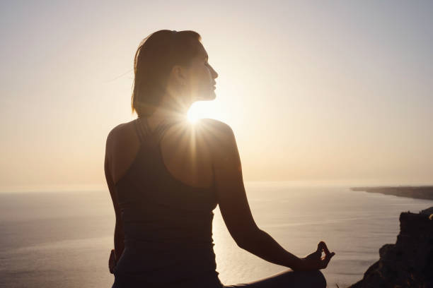 istock Young woman practicing yoga over sunset sea 1255587225