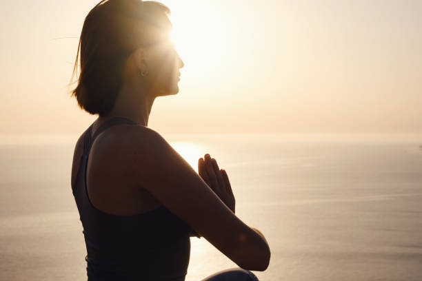 istock Young woman practicing yoga over sunset sea 1255587228