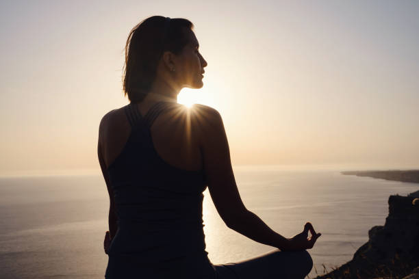 istock Young woman practicing yoga over sunset sea 1255587273