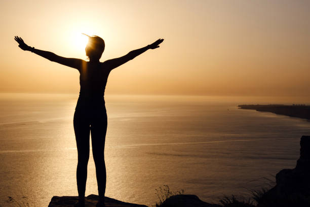 istock strong confidence woman open arms under the sunrise at seaside 1255587278