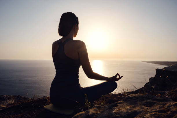 istock Young woman practicing yoga over sunset sea 1255587939