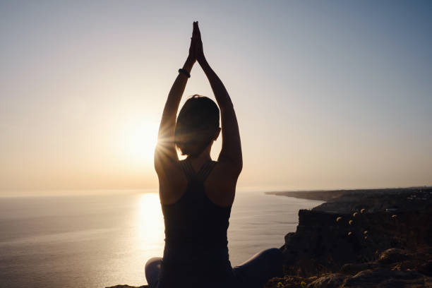 istock Young woman practicing yoga over sunset sea 1255587983