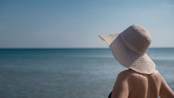 istock Beautiful Young Woman At Beach Wearing Hat 1255587997