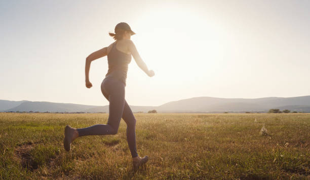 istock Jogging woman running in summer field at sunset 1255588208