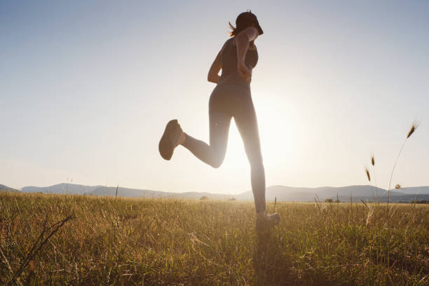 istock Jogging woman running in summer field at sunset 1255588235