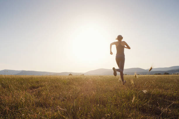 istock Jogging woman running in summer field at sunset 1255588236
