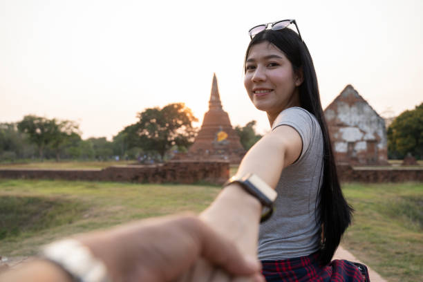 folgen sie mir zum tempel, ayutthaya thailand. weibliche touristin führt freund zu thai-tempel. menschen reisen konzept. - thailand asia famous place stone stock-fotos und bilder