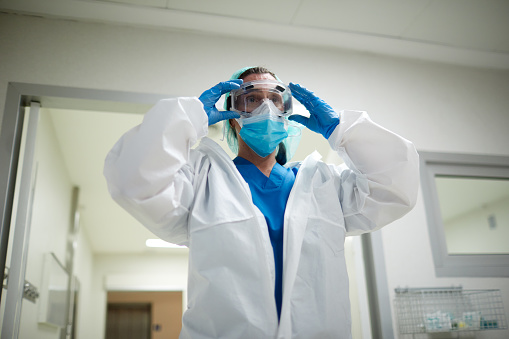 One female doctor getting dressed with PPE protective clothes.