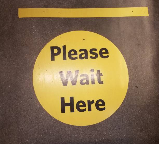 istock yellow please wait here social distancing sign 1255589680