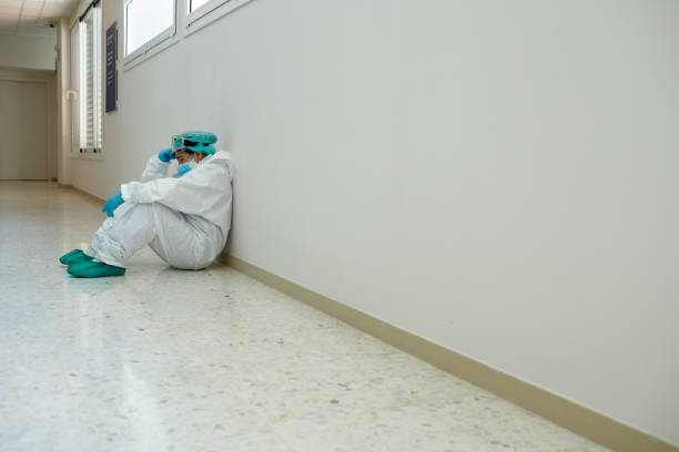 un trabajador de la salud cansado después de la cirugía en ropa de trabajo protectora covid. - doctor tired protective workwear sadness fotografías e imágenes de stock