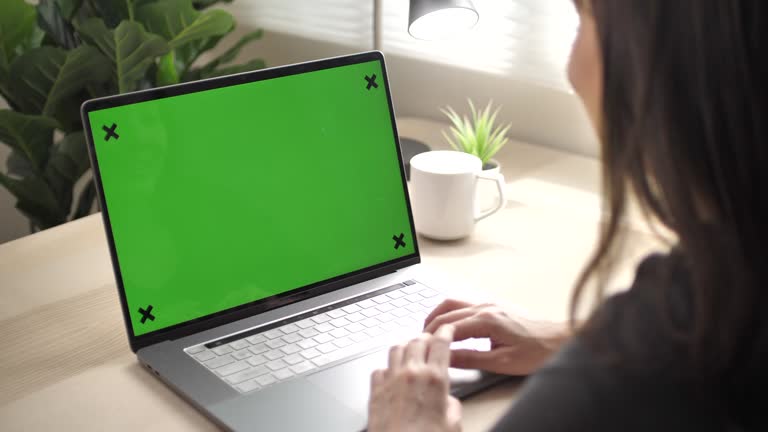 Asian Woman with green screen on laptop at home