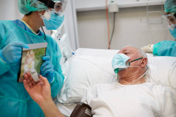 A COVID patient is looking at a picture of her granddaughter at the ICU A COVID patient is looking at a picture of her granddaughter at the ICU intensive care unit photos stock pictures, royalty-free photos & images