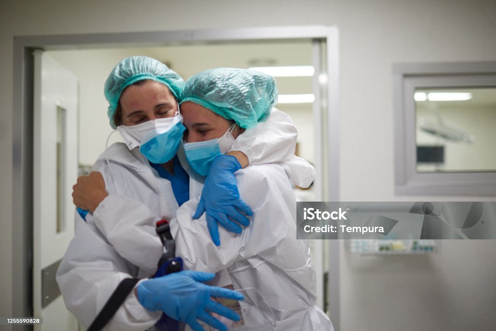 Two healthcare workers hug in celebration of a successful surgery procedure Two doctors hug in celebration of a successful surgery procedure Nurse Stock Photo