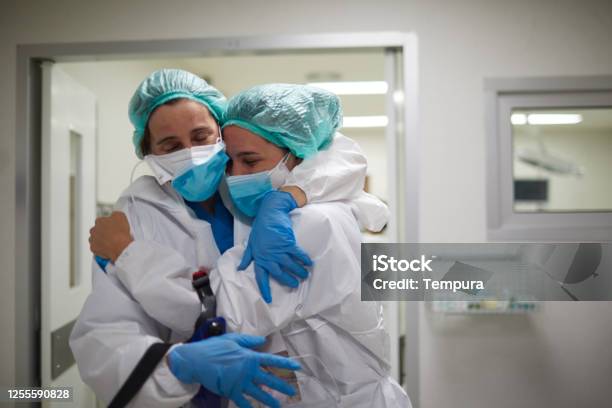 Two Healthcare Workers Hug In Celebration Of A Successful Surgery Procedure Stock Photo - Download Image Now