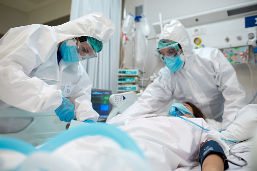 Trabajadores sanitarios ajustando el equipo a un paciente COVID. photo