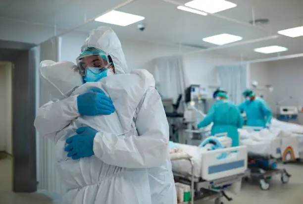 Two healthcare workers hug and support each other.