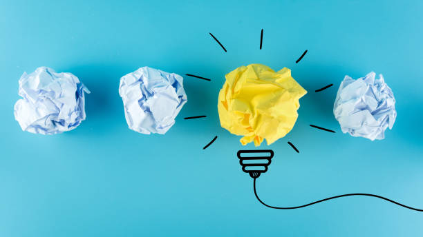 istock Inspiration concept crumpled paper light bulb metaphor for good idea, New Idea Concept. Crumpled Paper Balls on blue background. 1255593975