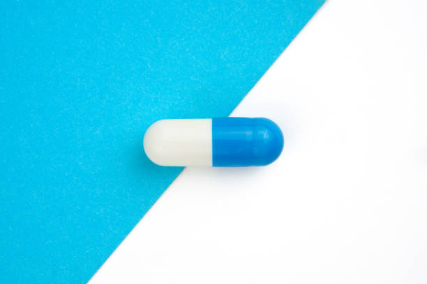 istock blue and white capsules medicine on white and blue duotone background. 1255594085
