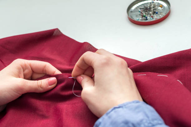 Seamstress sews clothes by hand. Woman's hands. Close-up. Handcraft concept. stock photo
