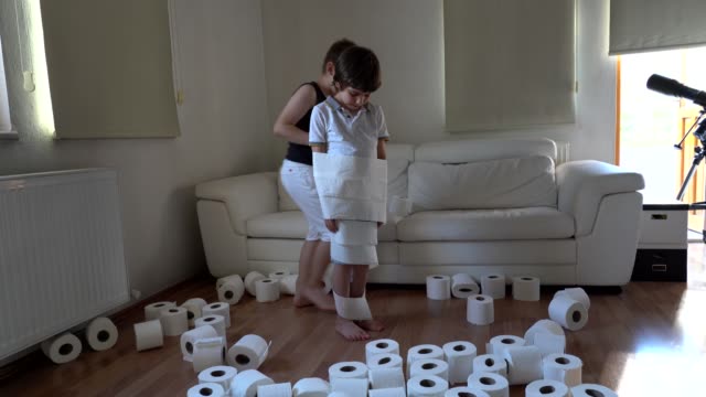 Little boys plays with toilet papers when she is bored at home during pandemic