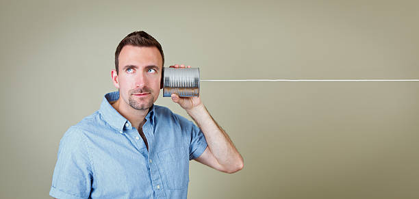 homem ouvindo telefone de lata - telephone can communication tin can phone - fotografias e filmes do acervo