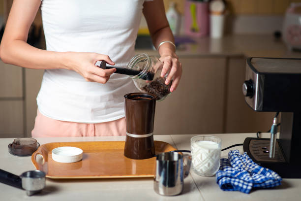 istock Woman inserting coffee beans into the grinder in the kitchen at home 1255598611
