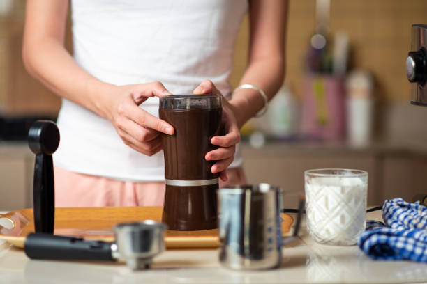 istock Woman using coffee grinder to get powder while making coffee at home 1255598663