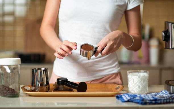 donna manomette la polvere di caffè nel portafiltro mentre fa il caffè a casa - tampering foto e immagini stock