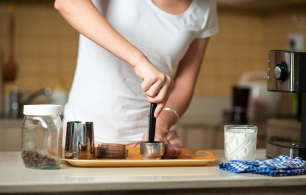 femme altérer la poudre de café dans le portafilter tout en faisant le café à la maison - tampering photos et images de collection