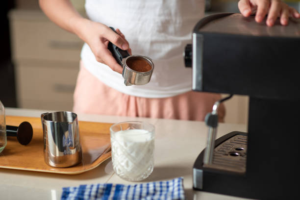 istock Woman using small home coffee maker to brew espresso at home 1255599378