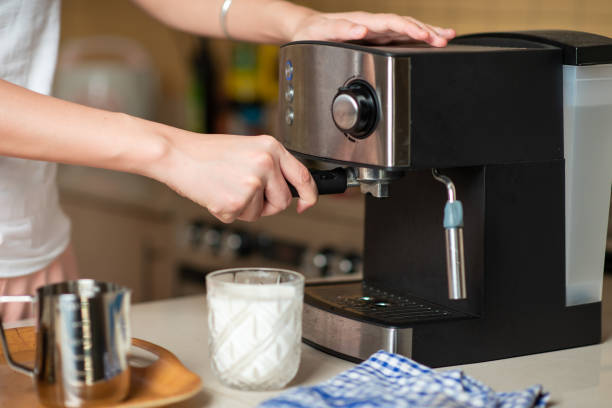 istock Woman using small home coffee maker to brew espresso at home 1255599408