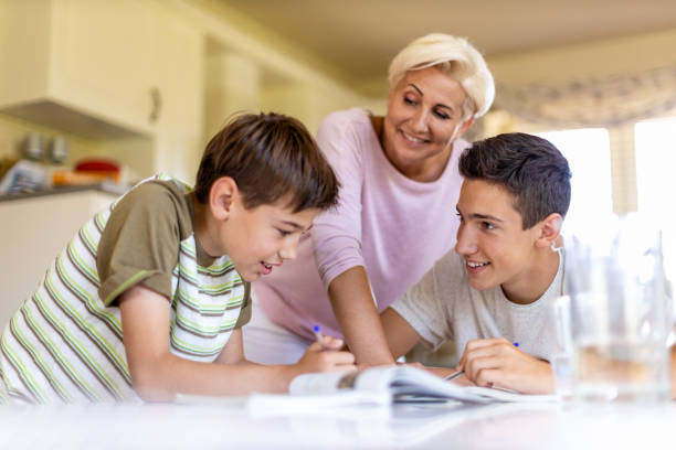 istock Mother helping her kids doing homework at home 1255601003