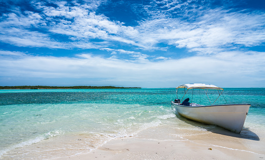 Small bote on the beach at Los Roques National Park, Venezuela during a beautiful and sunny day in a paradisiac island with plenty of sugar white sand.