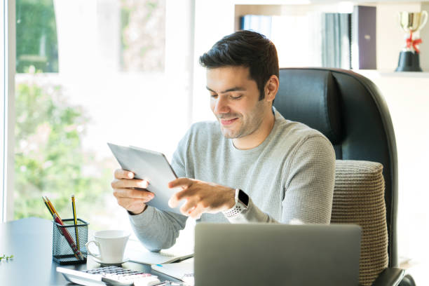istock Business people are sitting at home, mobile, laptop and tablet on the table. Young man using tablet. 1255602452
