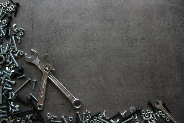 Frame or border made of old bolts and nuts. Industrial style. Wrench tool, old nuts and bolts of different sizes top view photo. Grey textured concrete background with copy space. Handyman tools close up picture. Home renovation concept. work tool nail wood construction stock pictures, royalty-free photos & images