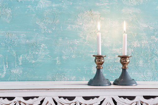 two shabbat candlesticks with burning candles over wooden table