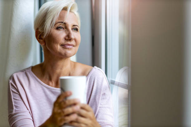 istock Relaxed woman at home sitting at the window 1255603959