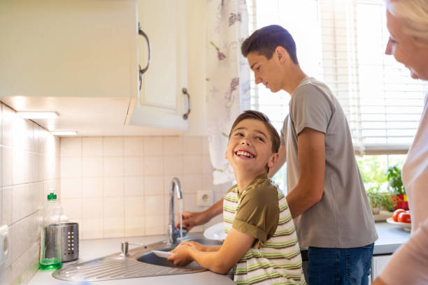 istock Two boys washing the dishes in the kitchen sink 1255603986