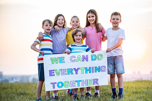 Children holds a message “we can do everything together” in public park