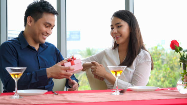 istock Romantic couple giving gift to lover at restaurant 1255605160
