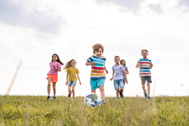 istock Happy kids plays with ball in nature 1255605257