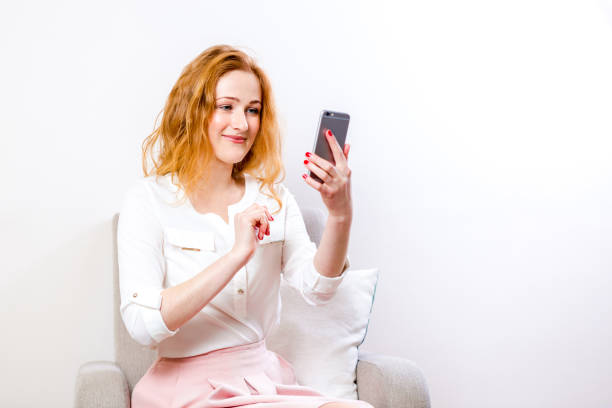 istock young woman blogger using mobile phone for interaction video calling. Female talking via messenger app having video chat on mobile phone. Communication, technology and online concept 1255607811