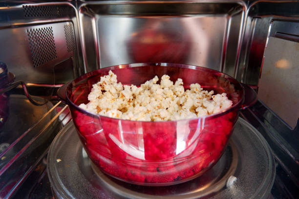 Popcorn prepared in microwave oven. Popcorn prepared in a red plastic microwave dish in a microwave oven. Close-up. inside microwave stock pictures, royalty-free photos & images