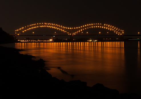 Hernando de Soto Bridge at night, with the bridge lights reflected in the Mississippi