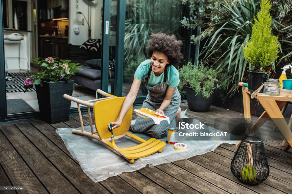 La mujer está coloreando una silla en casa - Foto de stock de Vida doméstica libre de derechos