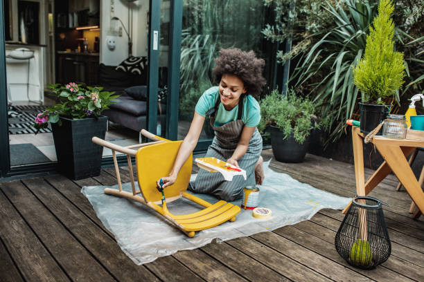 Woman is coloring a chair at home Female artist painting vintage chair in yellow color with a paintbrush in the back yard craft product photos stock pictures, royalty-free photos & images