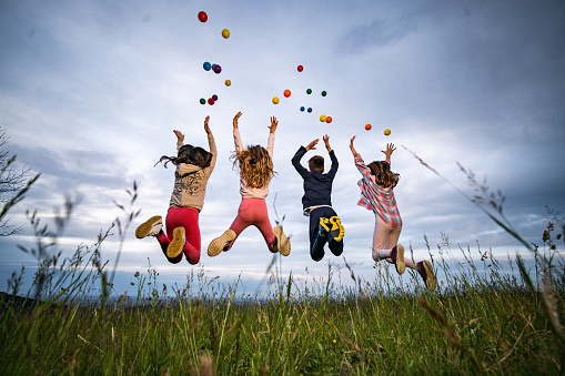 Children jumping while throwing a colorful balls in the air