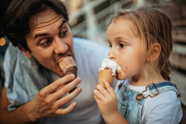 It's sweet like you are Father and daughter licking ice cream in public park licking ice cream cone stock pictures, royalty-free photos & images