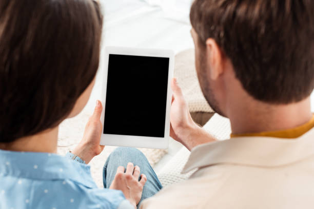 istock Back view of young couple holding digital tablet with blank screen 1255620486